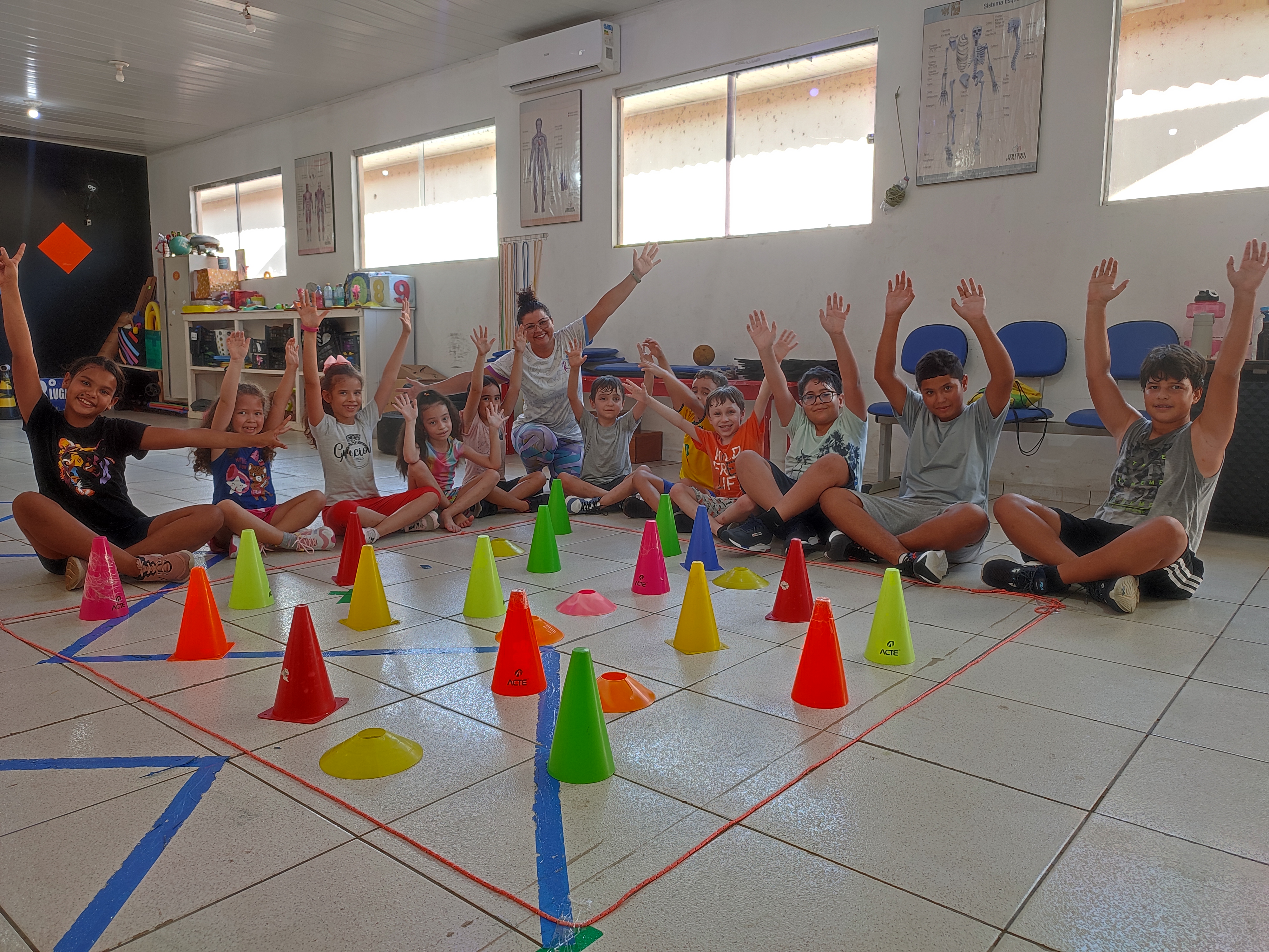 Crianças felizes levantando as mãos na aula da Tia Néia